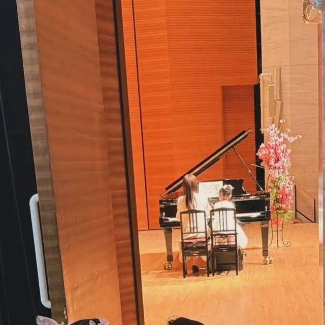発表会会場の舞台袖から見た遠景。グランドピアノと桜装飾。（仮画像）
